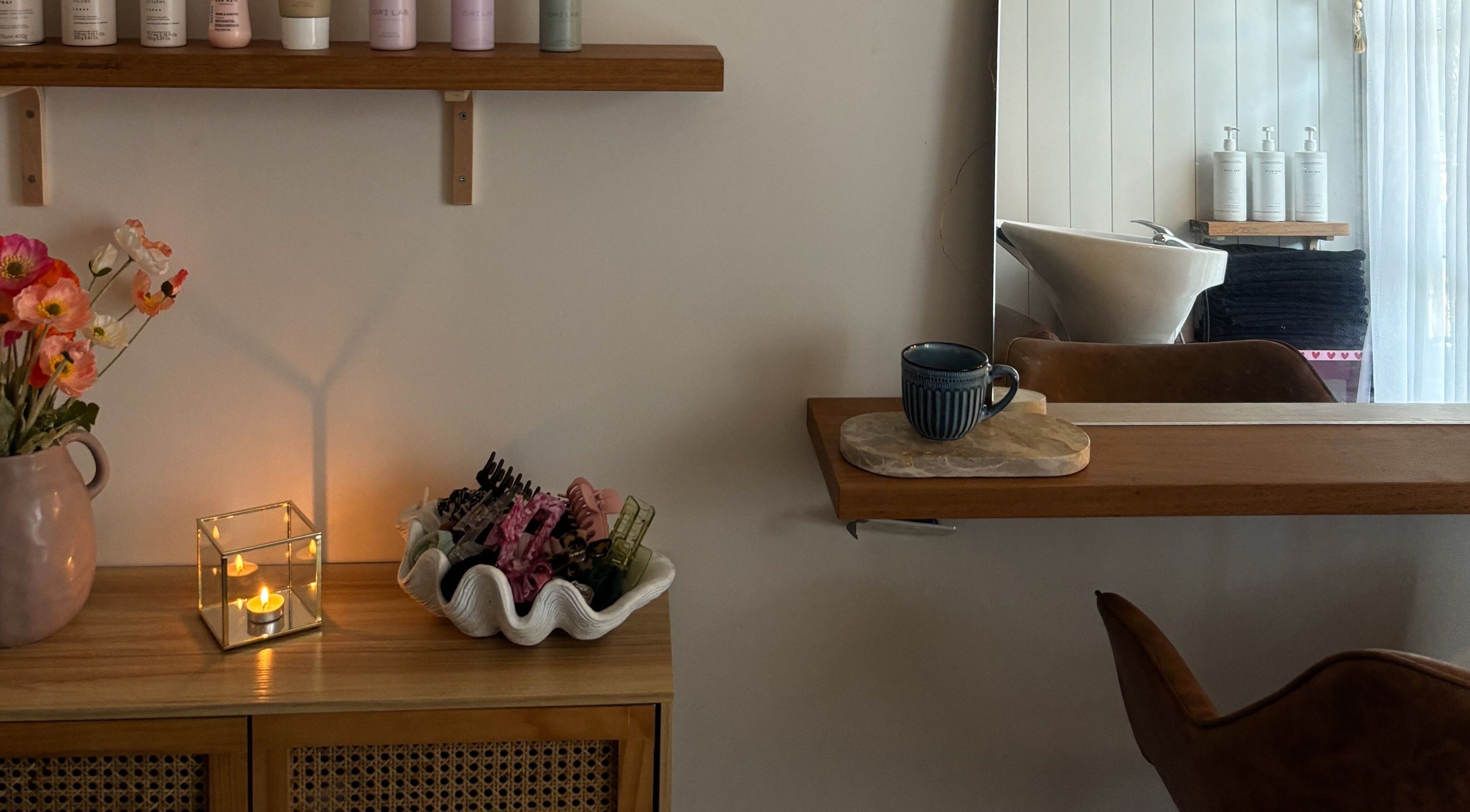 Serene salon corner at Sandy Salon, Sandy Beach, New South Wales, AU with flowers, cup, and hair accessories.