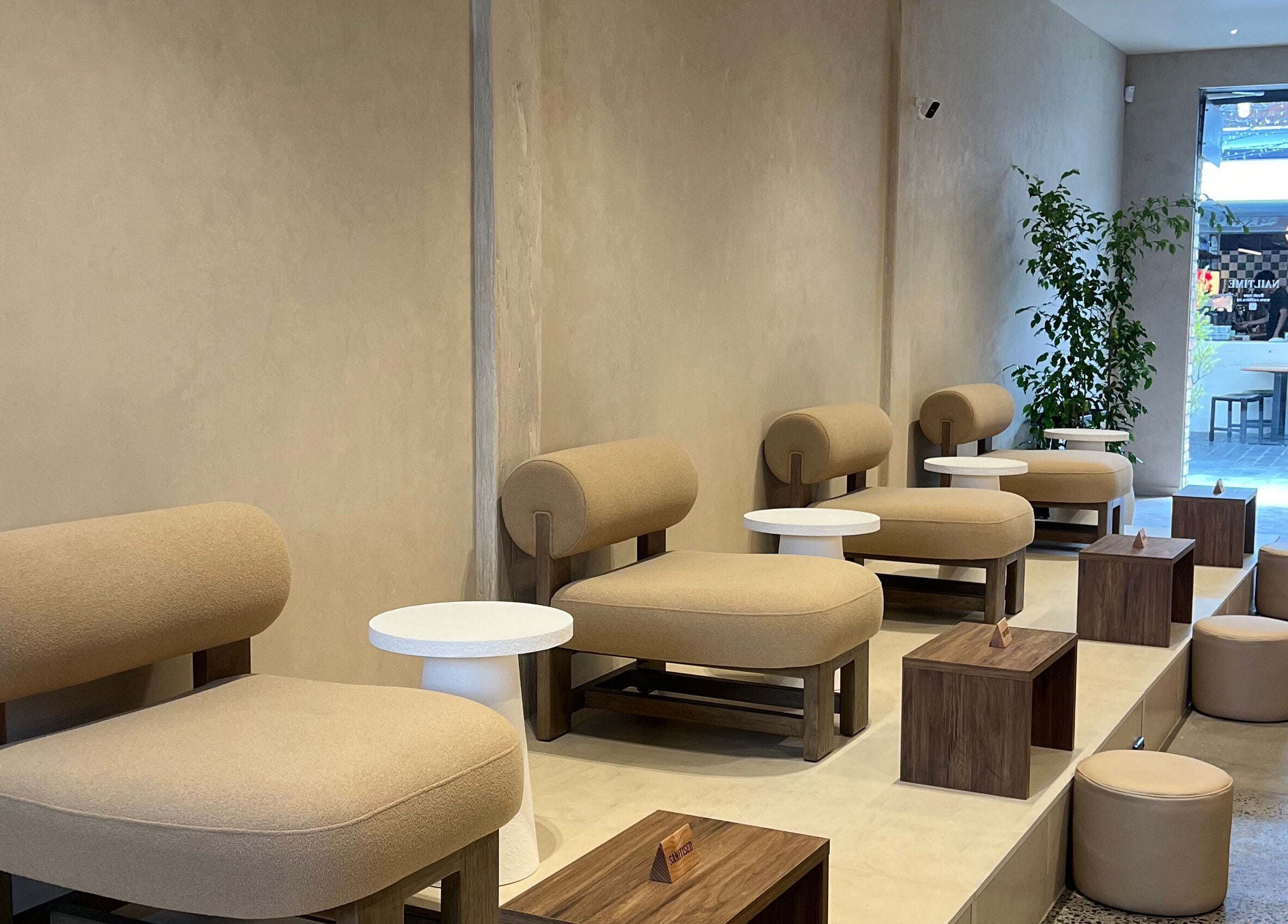 Modern seating area at NAILTIME in Auckland, NZ, featuring stylish beige chairs and sleek decor.