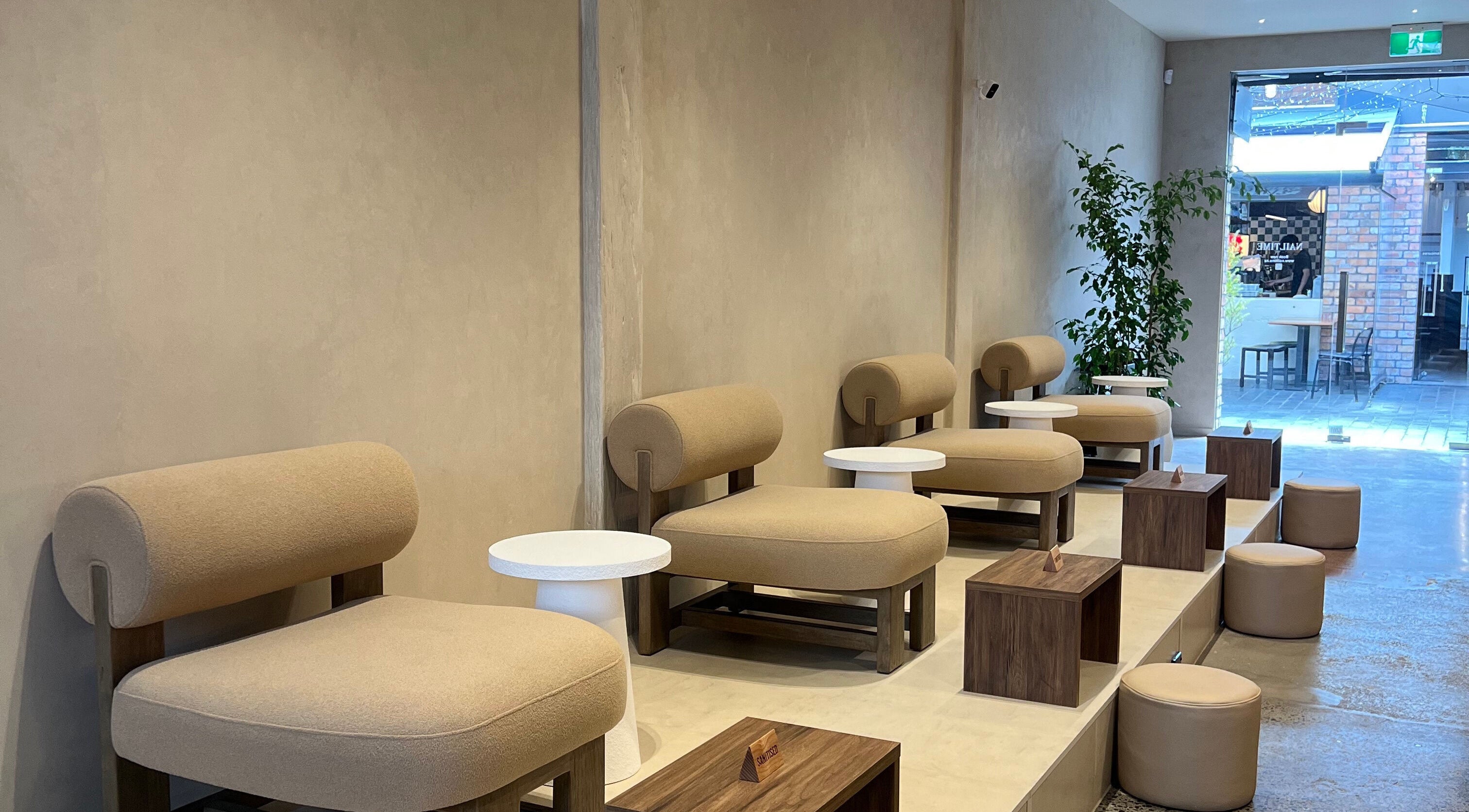 Modern seating area at NAILTIME in Auckland, NZ, featuring stylish beige chairs and sleek decor.