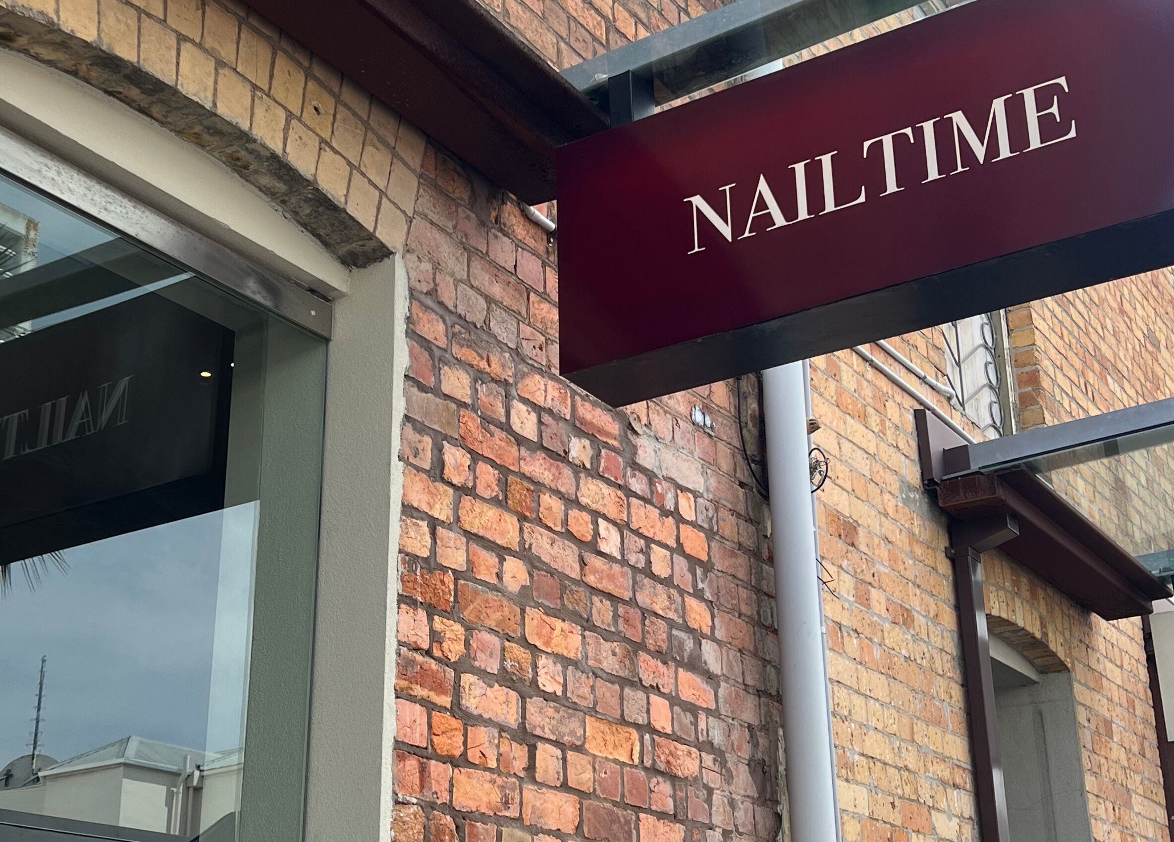 NAILTIME sign on brick exterior in Auckland, NZ, showcasing boutique beauty venue ambiance.