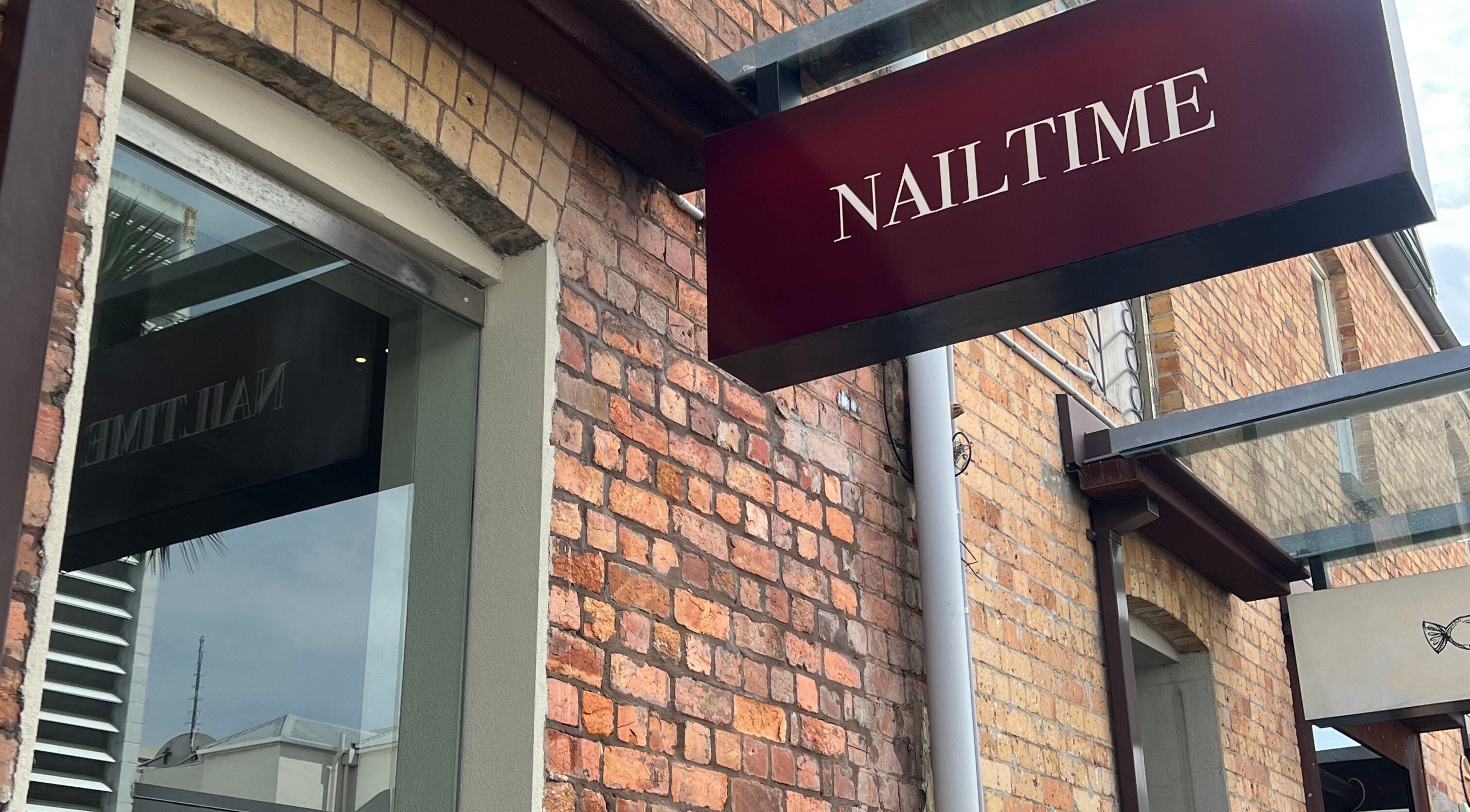 NAILTIME sign on brick exterior in Auckland, NZ, showcasing boutique beauty venue ambiance.