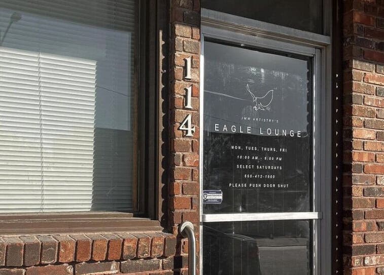 Entrance to Eagle Lounge, Brookfield, Missouri, US, showcasing a stylish glass door and brick facade.