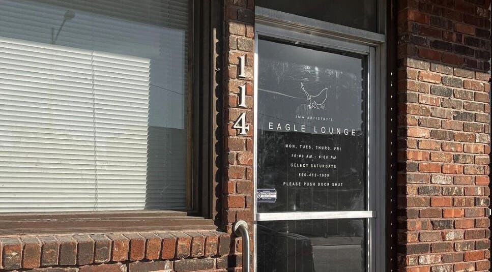 Entrance to Eagle Lounge, Brookfield, Missouri, US, showcasing a stylish glass door and brick facade.