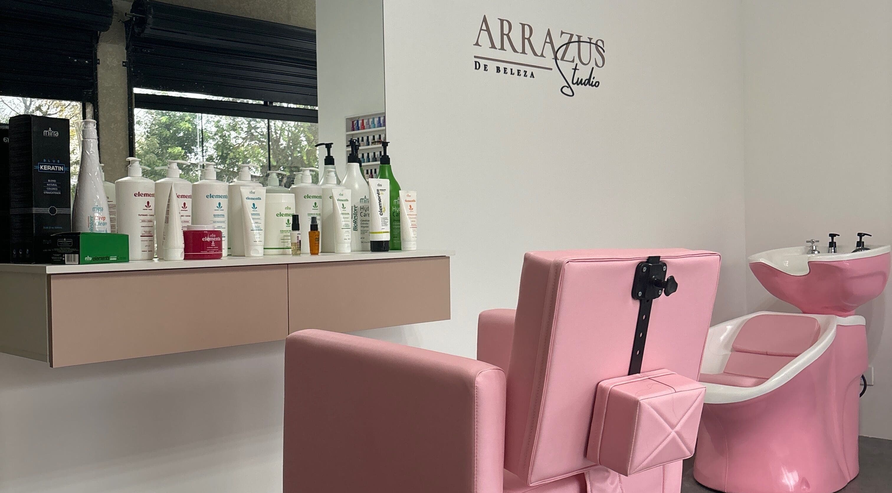 Interior do Arrazus Studio de Beleza com cadeira rosa e produtos na bancada, Paraná, Paraná, BR.