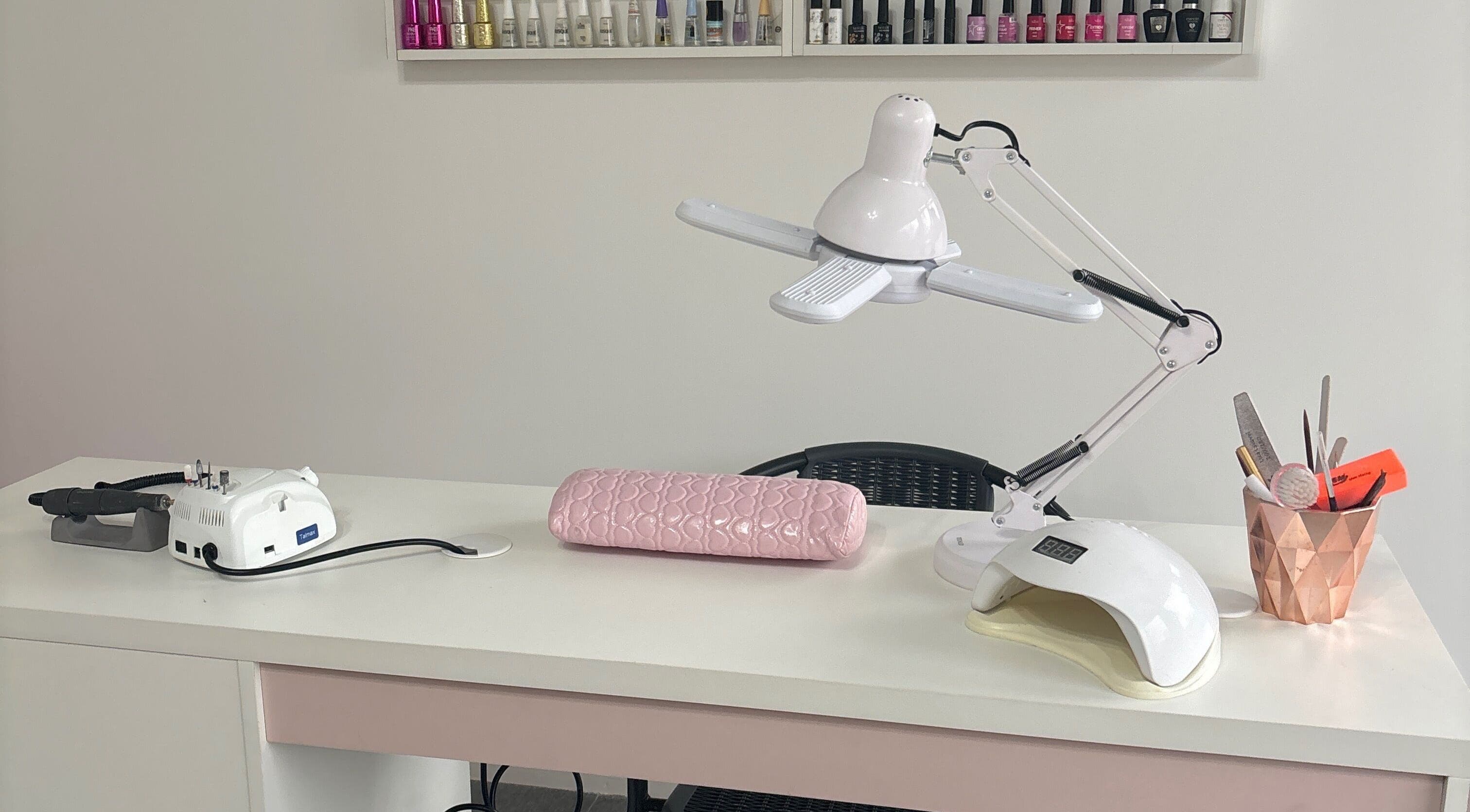 Mesa de manicure no Arrazus Studio de Beleza, Paraná, PR, com ferramentas e lâmpada moderna.