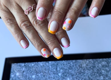 Colorful floral nail art at Freyas Beauty, Bream, England, GB, showcasing vibrant pink and orange designs.