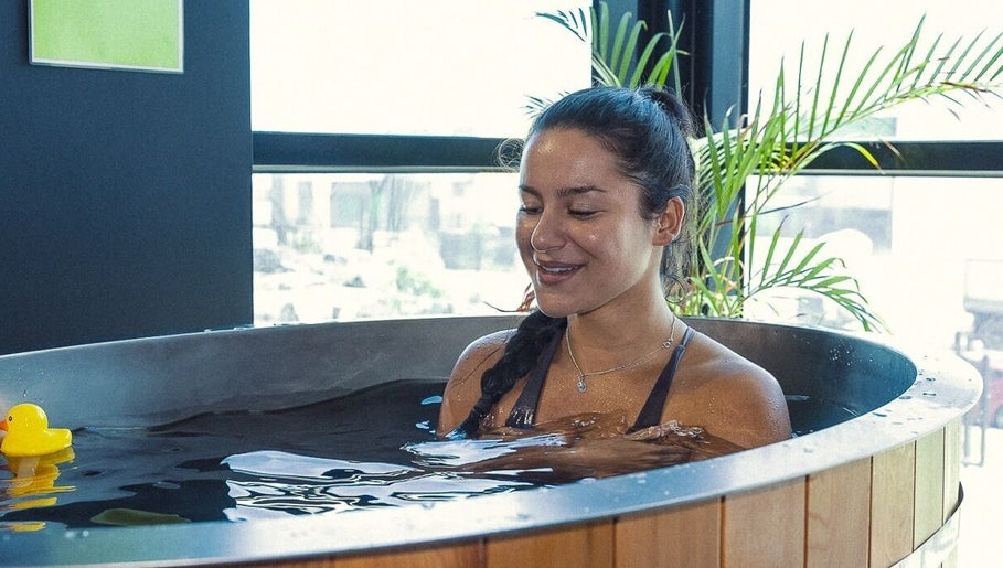 Woman relaxing in a tub at Energize Recovery, Melbourne, Victoria, AU, with a rubber ducky and lush plants.