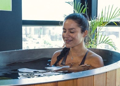 Woman relaxing in a tub at Energize Recovery, Melbourne, Victoria, AU, with a rubber ducky and lush plants.