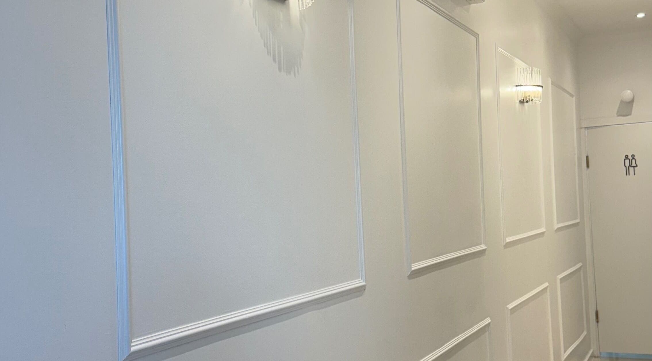 Bright hallway at The Smile Palette, London, England, GB with elegant wall panels and lighting.