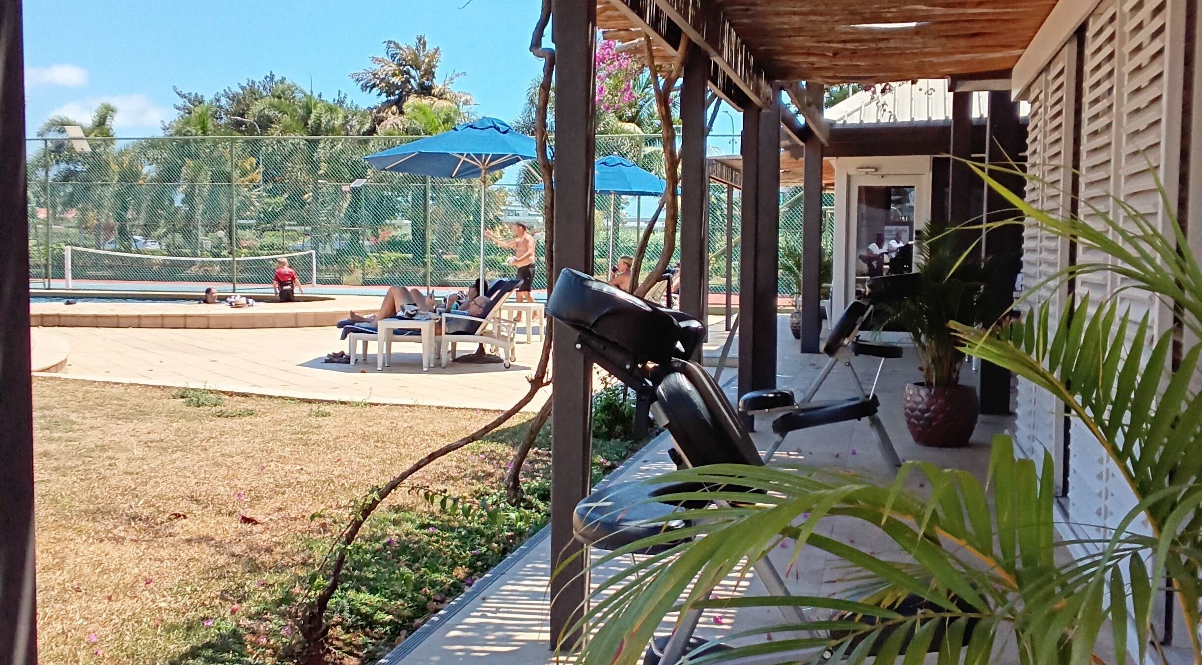 Relaxing poolside view at Nama Fiji, Nadi, Western Division, FJ, surrounded by palm trees and lounge chairs.