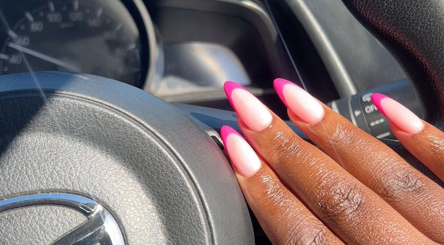 Elegant pink nails designed at House of Nails in Cape Town, Western Cape, ZA, on a car steering wheel.