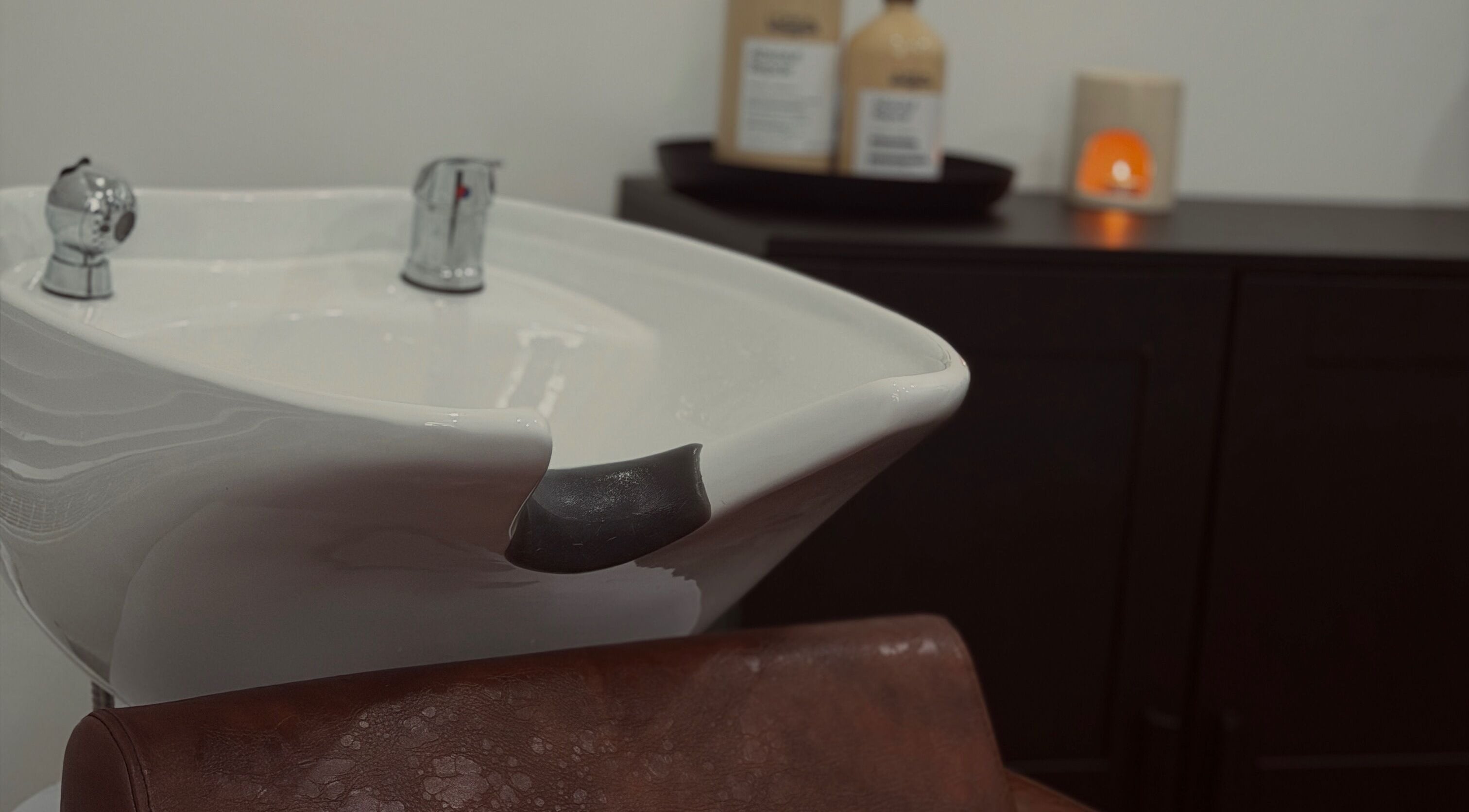 Hair washing station at MS Hairdressing in Colchester, England, GB with a modern sink and products.