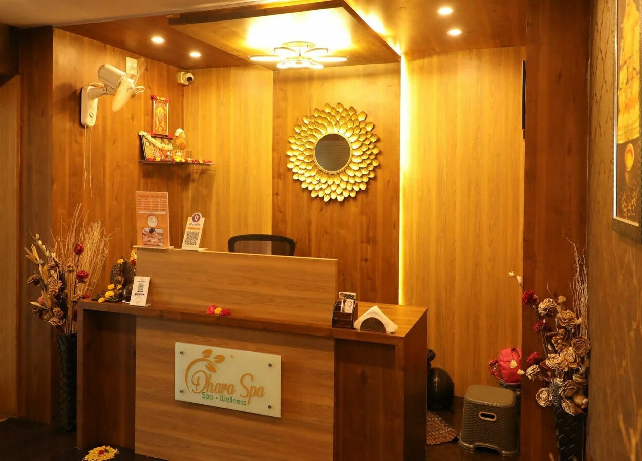 Warm reception at Dhara Spa - HSR Layout, Bengaluru, Karnataka, IN with wooden decor and elegant mirror.