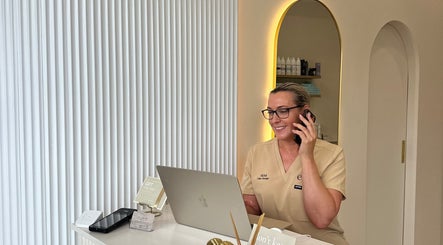 E-skin receptionist smiling while on phone at Mermaid Waters, Queensland, AU. Modern and welcoming atmosphere.