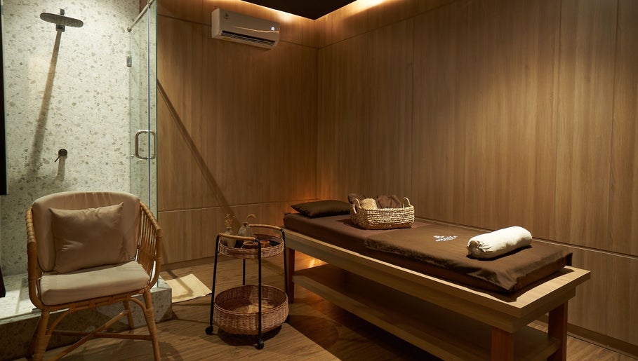 Tranquil therapy room at Amansa Spa and Wellness Solo, Central Java, ID with massage bed and cozy chair.