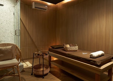 Tranquil therapy room at Amansa Spa and Wellness Solo, Central Java, ID with massage bed and cozy chair.