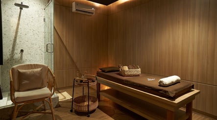 Tranquil therapy room at Amansa Spa and Wellness Solo, Central Java, ID with massage bed and cozy chair.