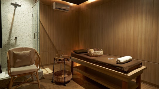 Tranquil therapy room at Amansa Spa and Wellness Solo, Central Java, ID with massage bed and cozy chair.