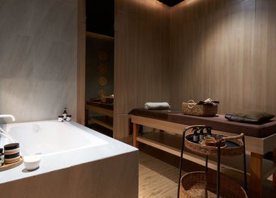 Relaxing treatment room at Amansa Spa and Wellness Solo, Central Java, Central Java, ID, with massage table and bathtub.