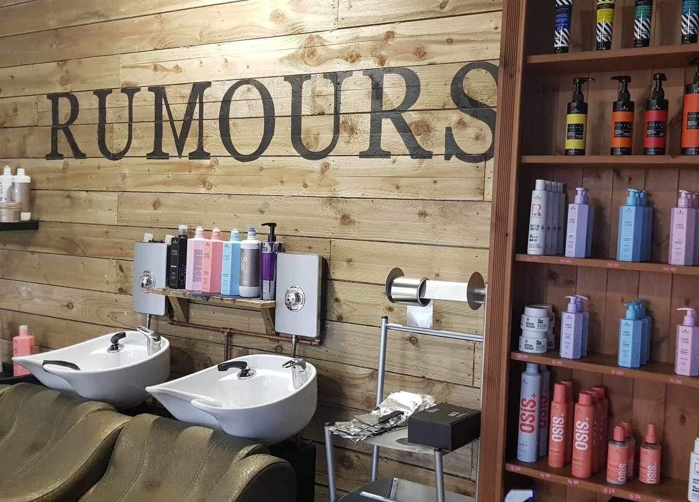 Interior of Rumours, a beauty salon in Brodick, Scotland, GB with wooden walls and colorful products displayed.