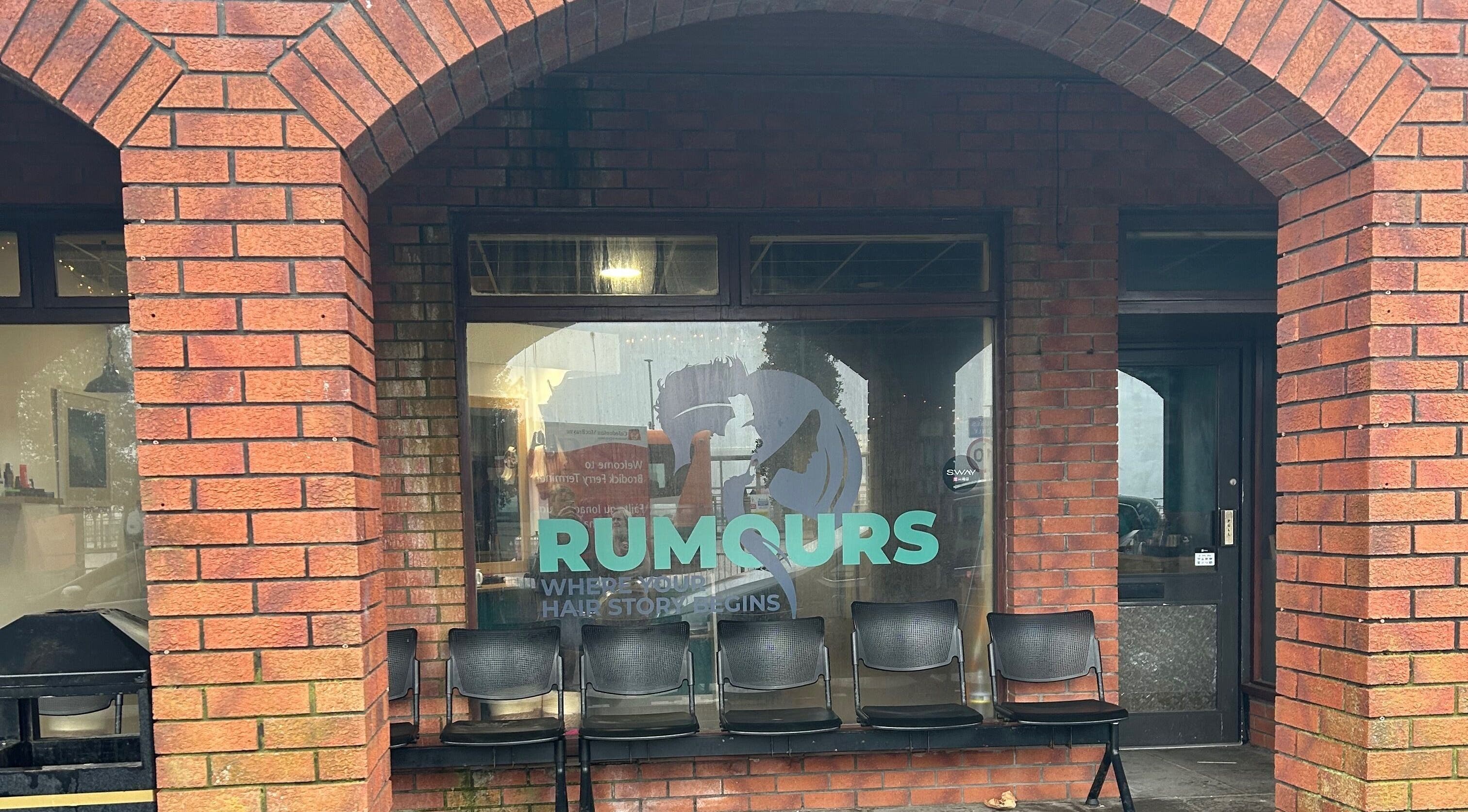 Exterior of Rumours salon, Brodick, Scotland, GB, showcasing welcoming seating and stylish signage.