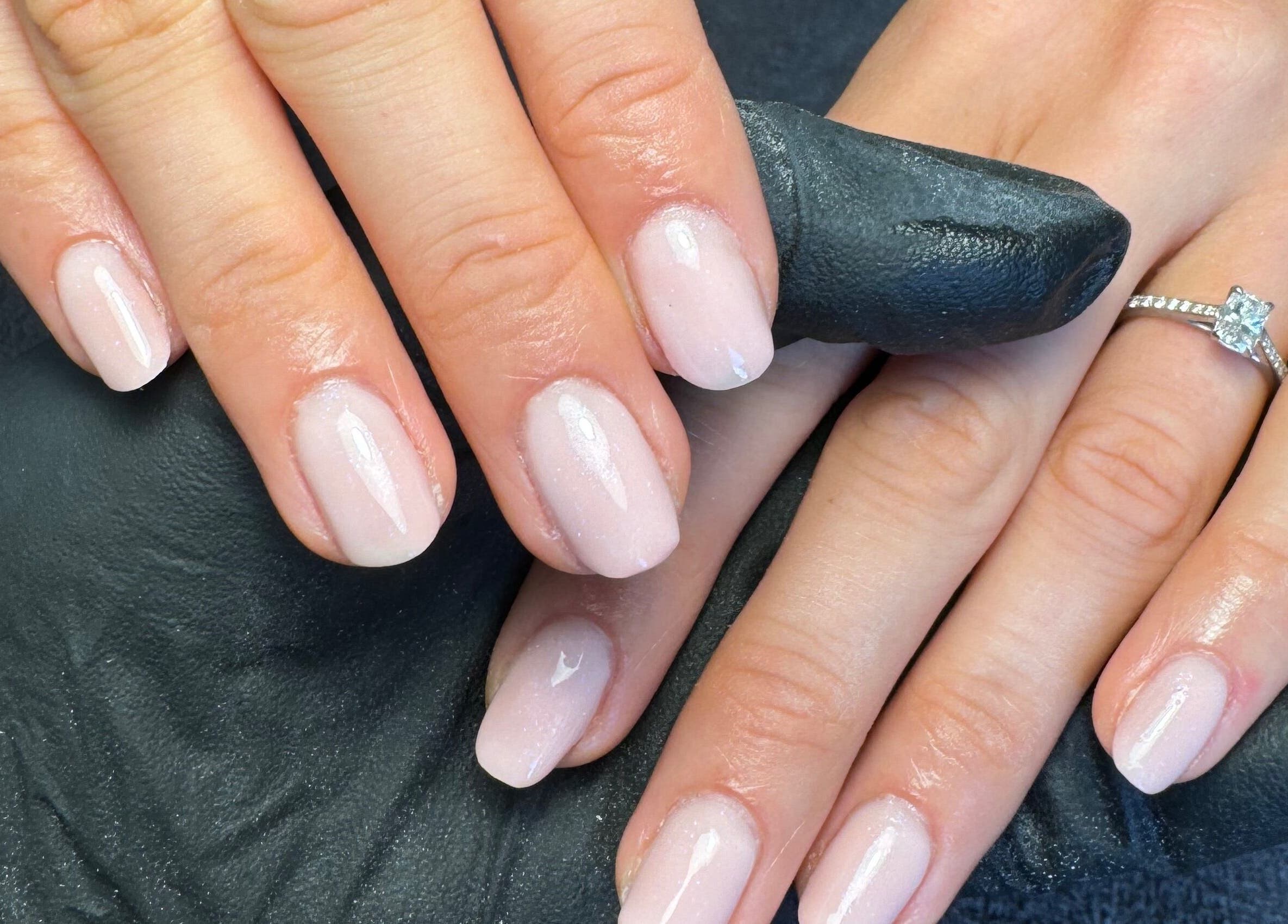 Freshly manicured hands at By Kadie, Throckley, England, GB with soft pink nails and a sparkling diamond ring.