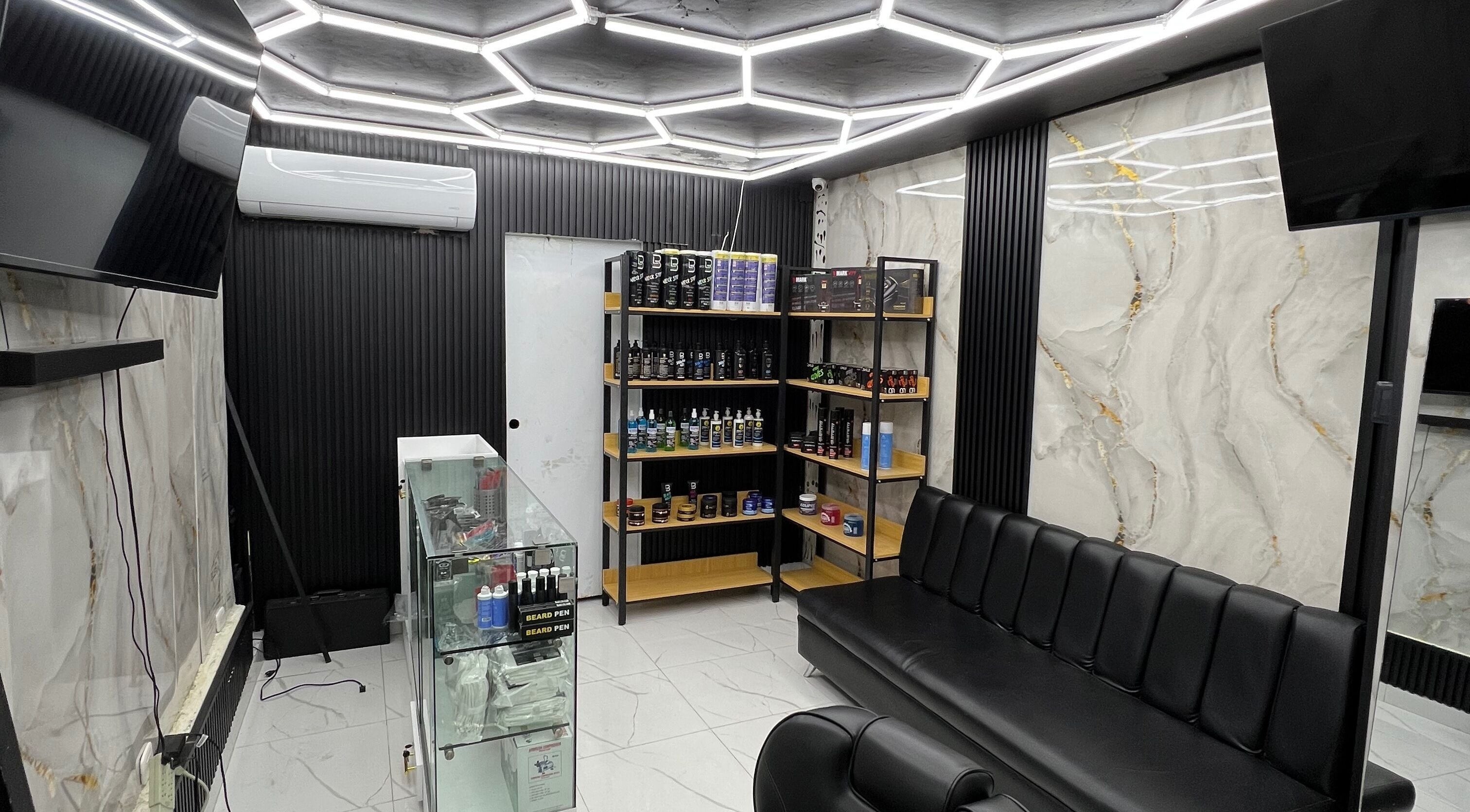 Interior moderno de GECS BARBER STUDIO en Santo Domingo, DO, con estantería y asientos elegantes.