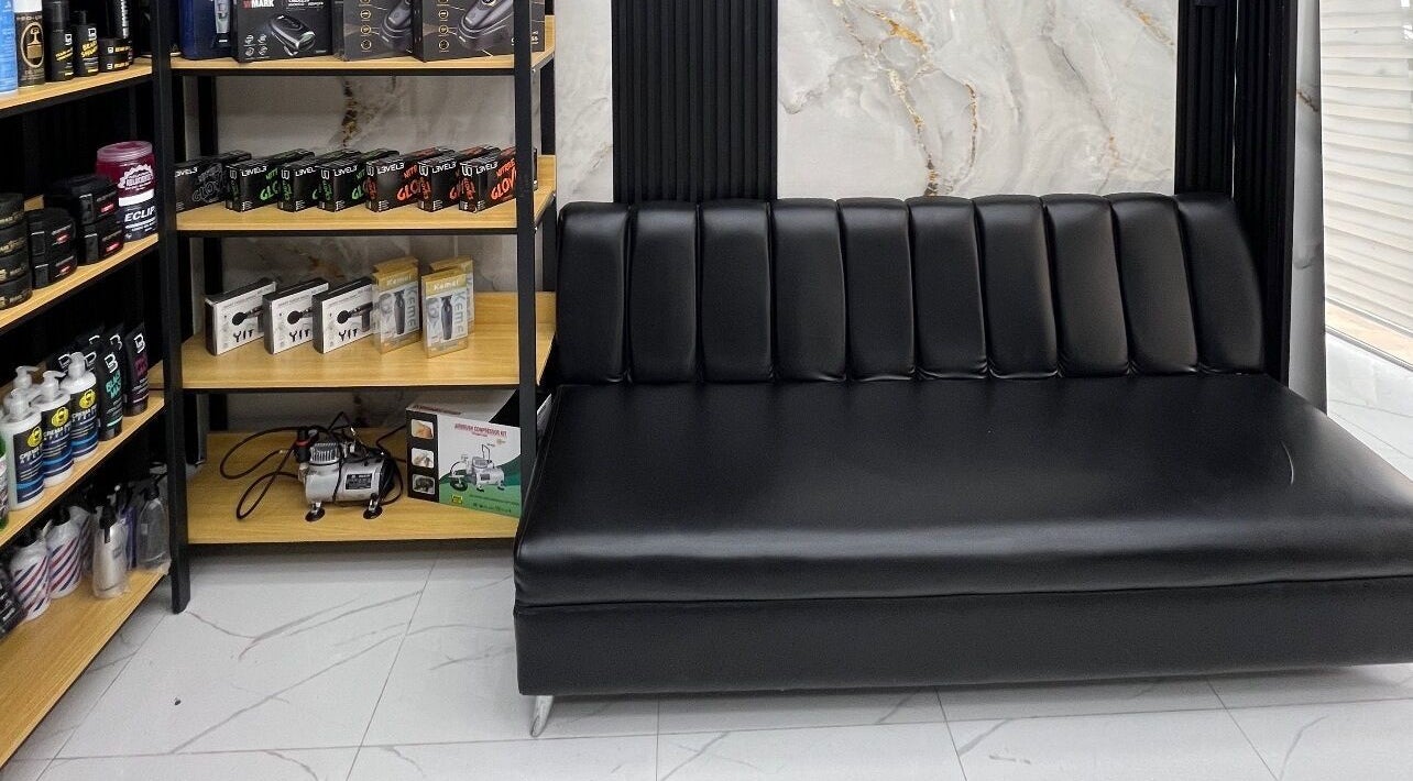 Sofá negro de diseño elegante en GECS BARBER STUDIO en Santo Domingo, DO, ideal para clientes.