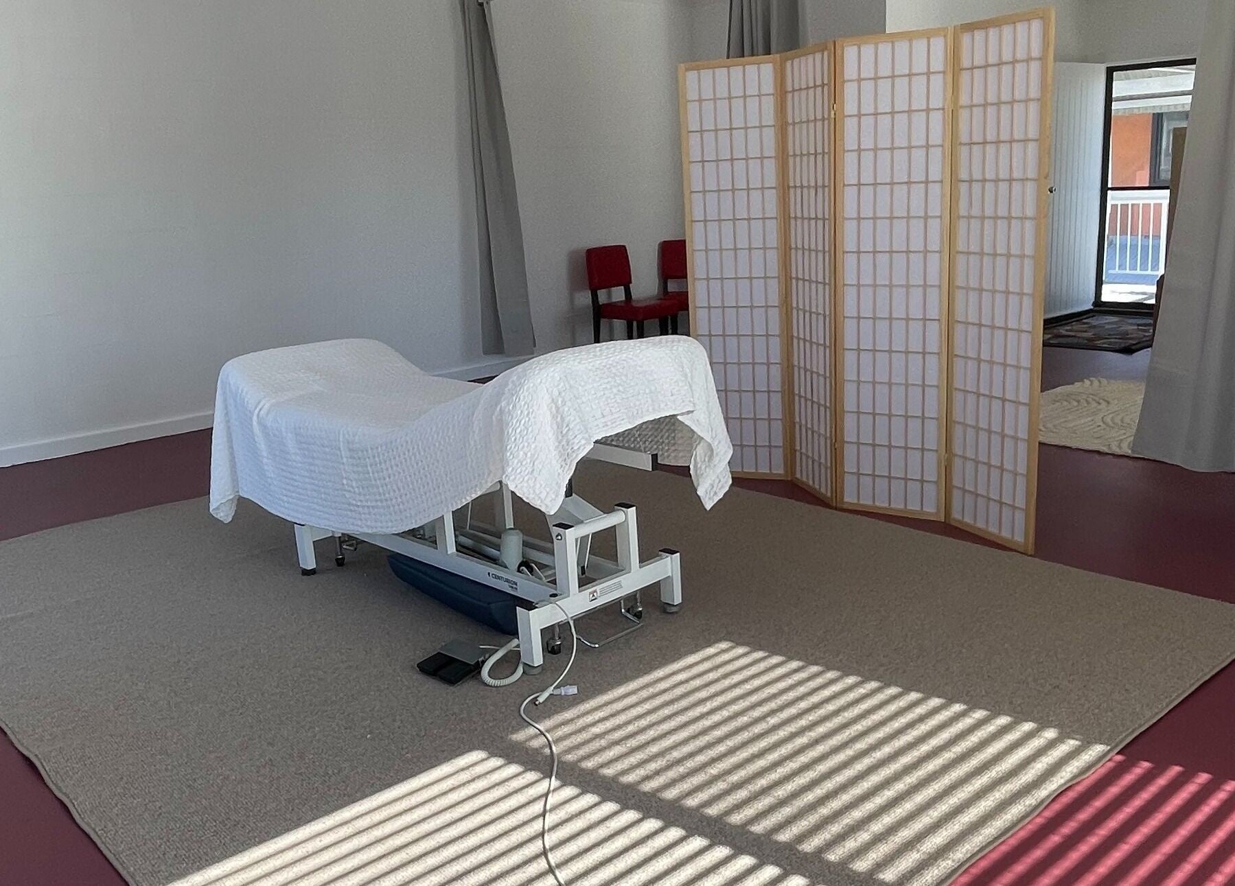 Tranquil massage room at The Biofield Body - Byron Bay, New South Wales, AU, with a white treatment bed.