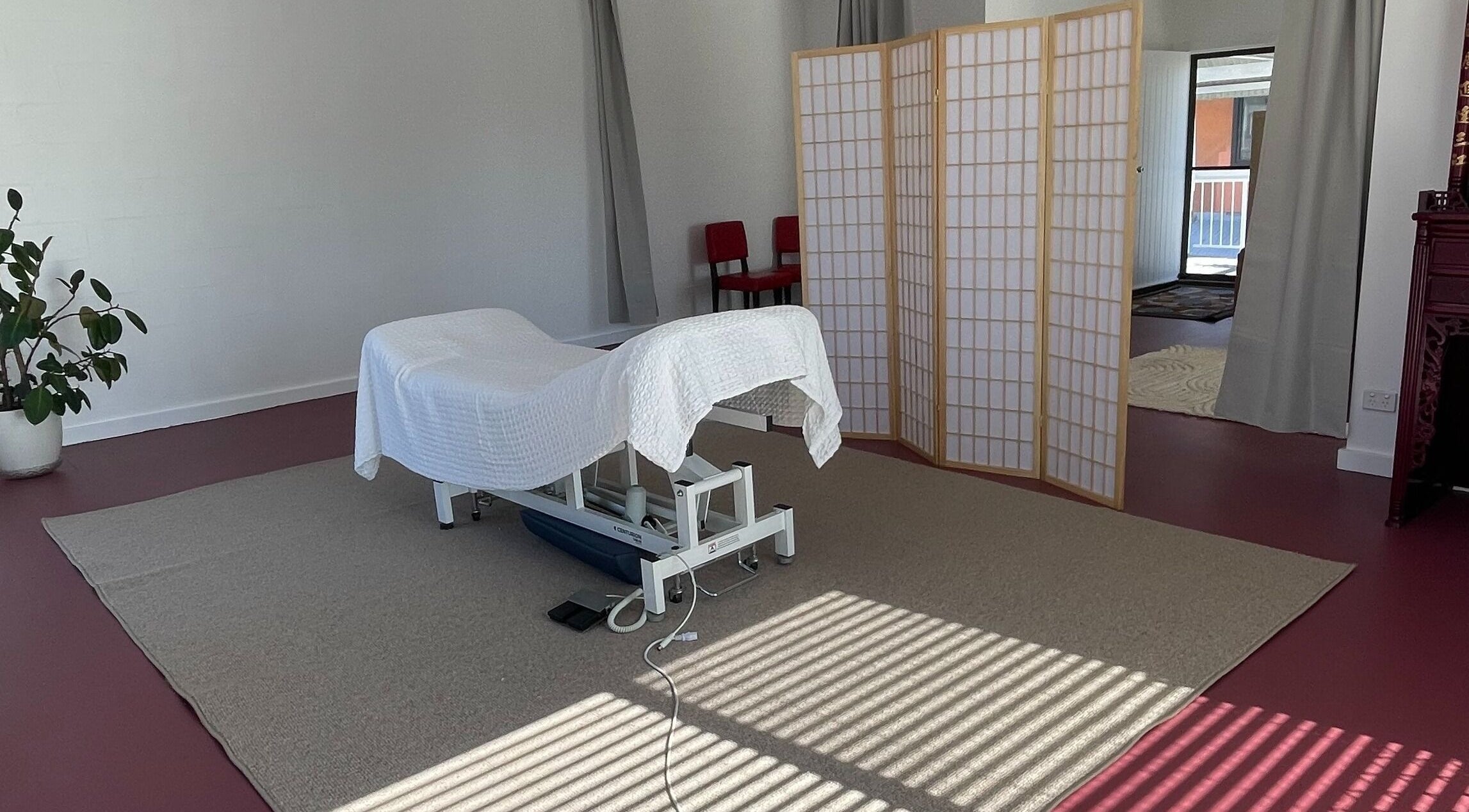 Tranquil massage room at The Biofield Body - Byron Bay, New South Wales, AU, with a white treatment bed.