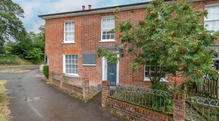 Exterior view of The Lash Lounge in Fakenham, England, GB showcasing a charming red brick facade with greenery.