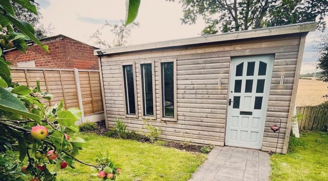 Charming garden cabin at Breathe and Bloom Holistics in Wakefield, England, GB, surrounded by lush greenery.