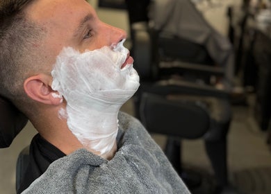 Een klant wordt geschoren bij Barbershop Houten, Houten, Utrecht, NL, met een zachte scheerschuim.