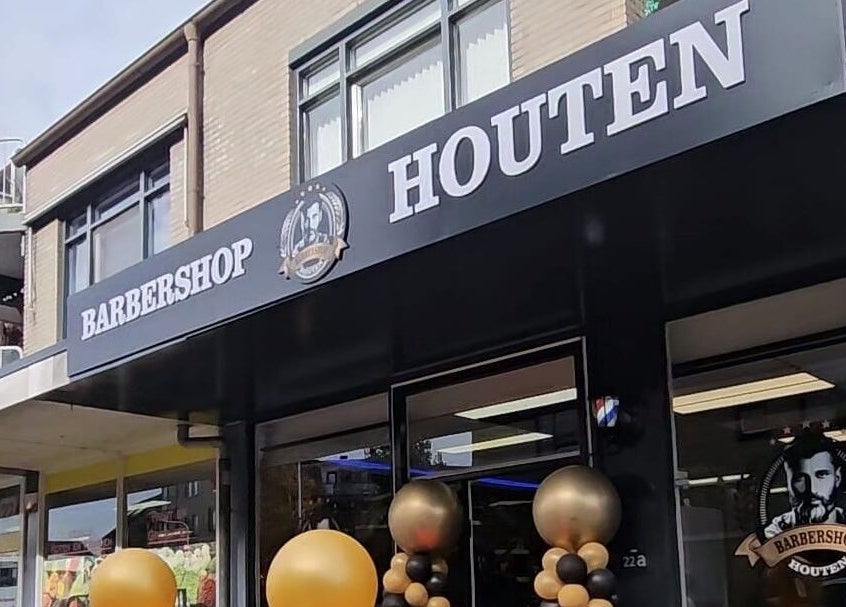 Barbershop Houten in Houten, Utrecht, NL, met stijlvolle zwart-wit gevel en ballondecoraties.