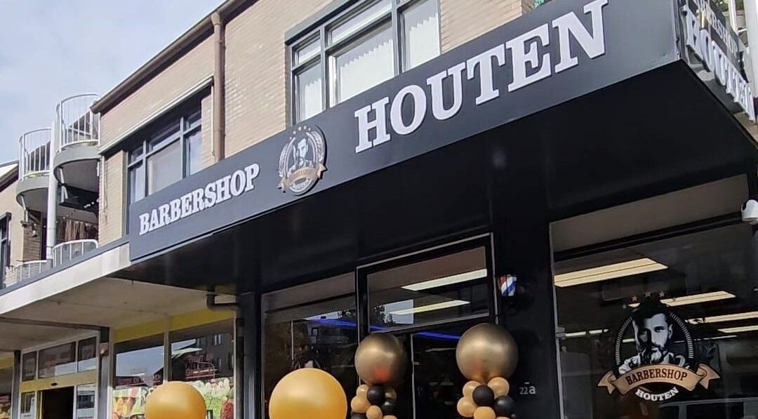 Barbershop Houten in Houten, Utrecht, NL, met stijlvolle zwart-wit gevel en ballondecoraties.