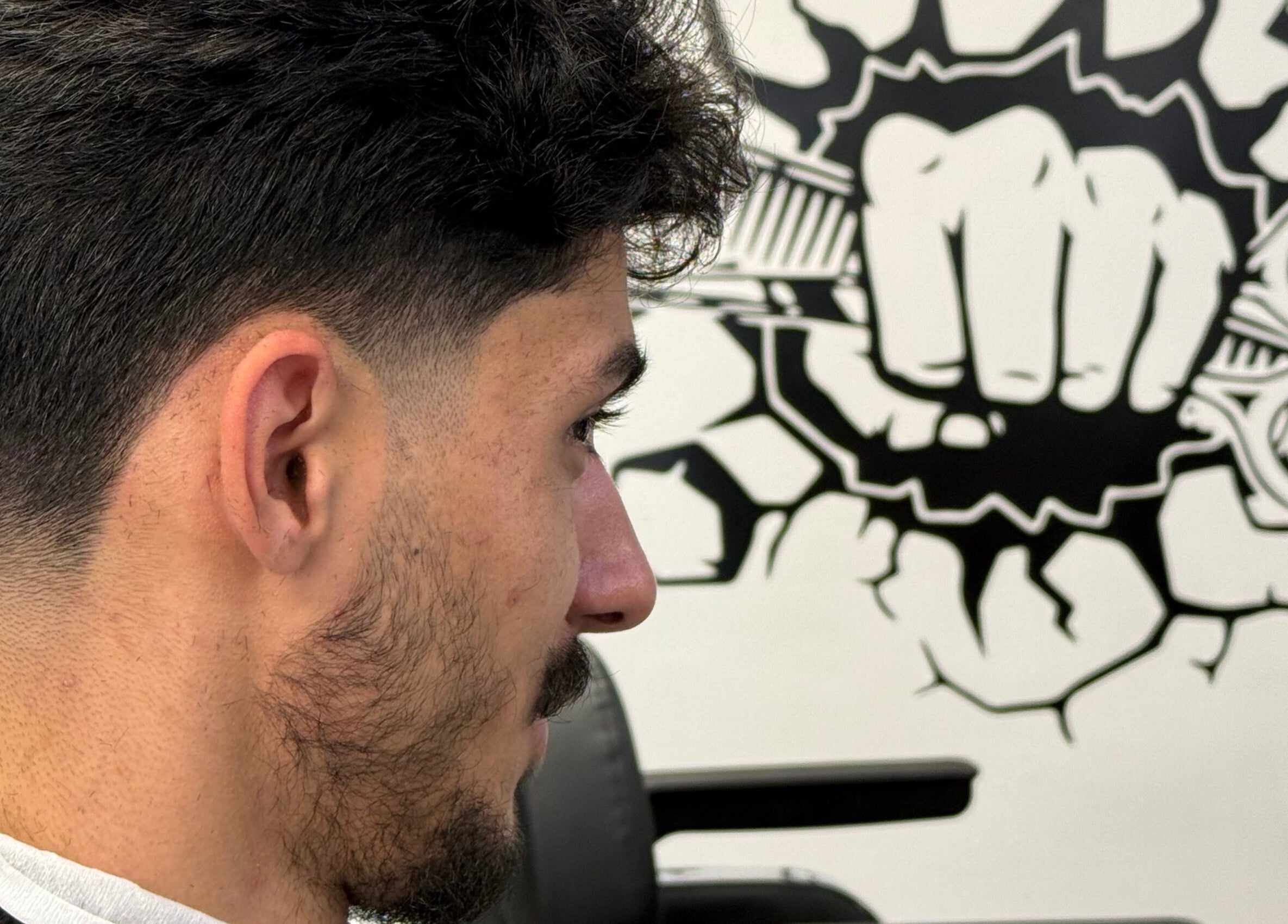 Strakke herenkapsel bij Barbershop Houten, Houten, Utrecht, NL, met een stijlvolle muurschildering.