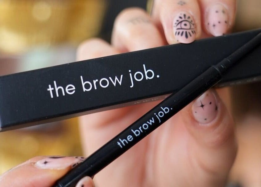 Close-up of 'the brow job.' eyebrow product in Chester, England, GB, held by hand with nail art.