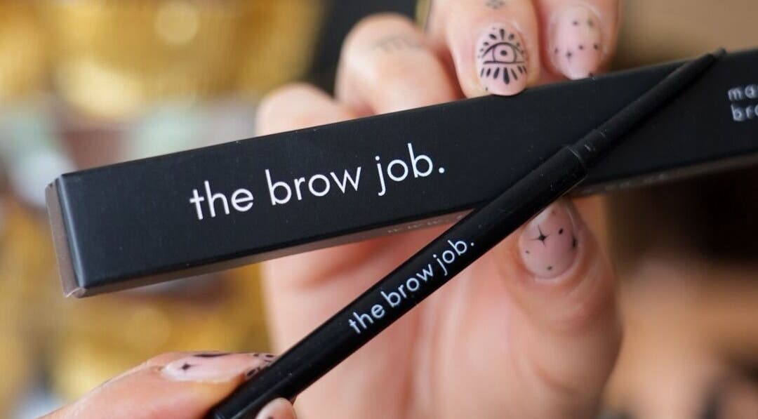 Close-up of 'the brow job.' eyebrow product in Chester, England, GB, held by hand with nail art.