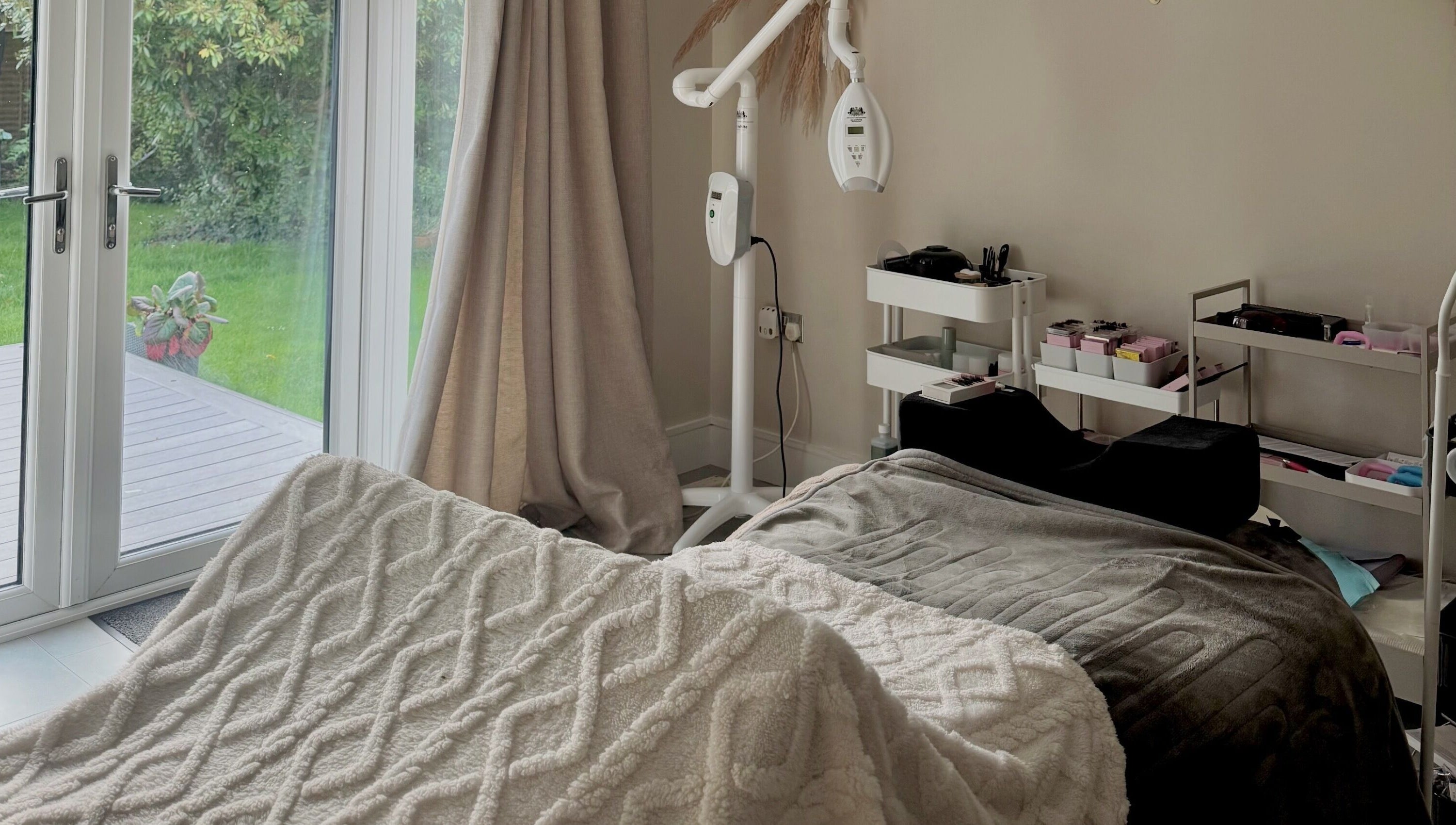 Cozy treatment room at Amber Rose Beauty, Poole, England, GB with a massage bed and garden view.