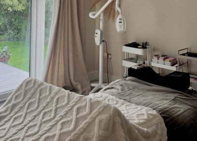 Cozy treatment room at Amber Rose Beauty, Poole, England, GB with a massage bed and garden view.