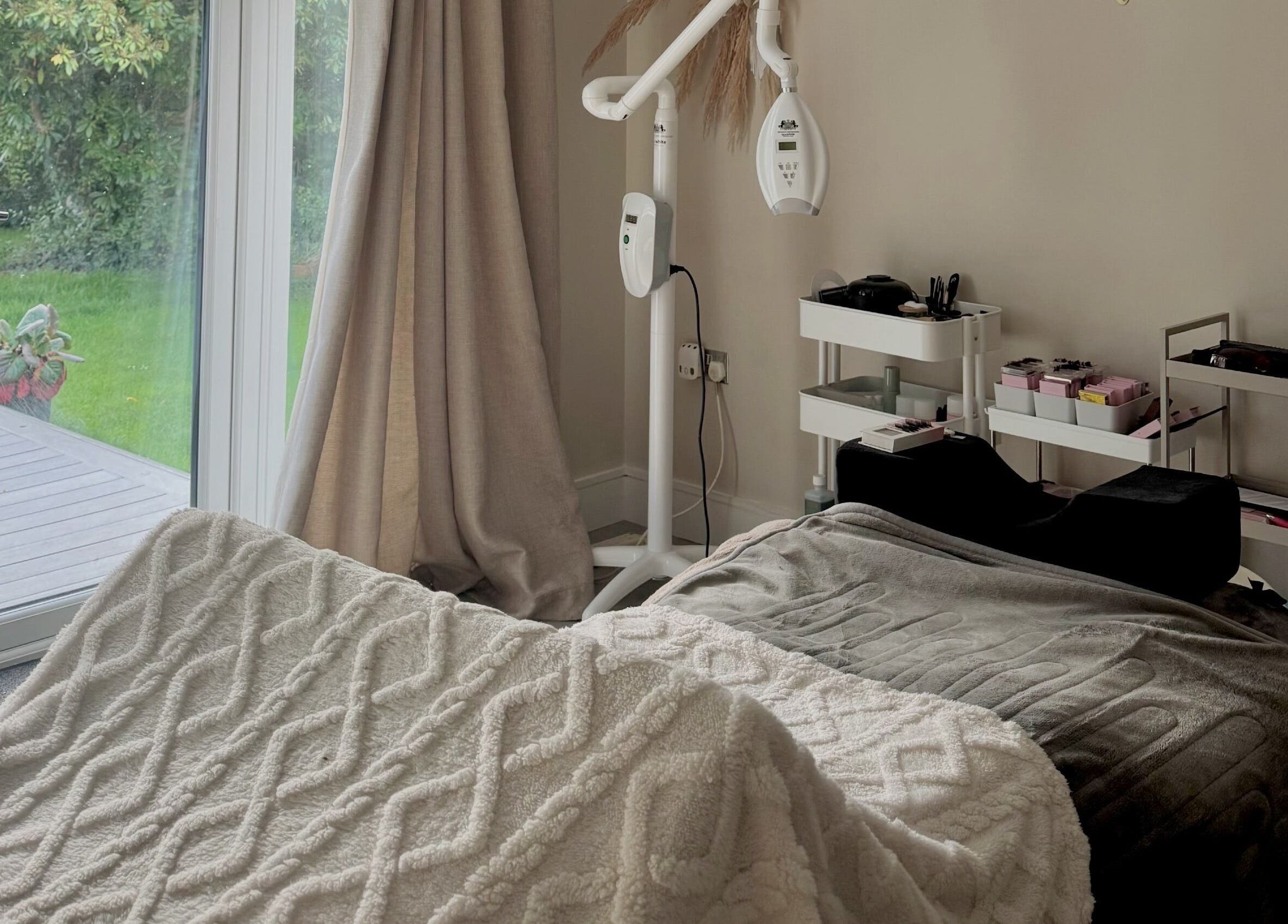 Cozy treatment room at Amber Rose Beauty, Poole, England, GB with a massage bed and garden view.