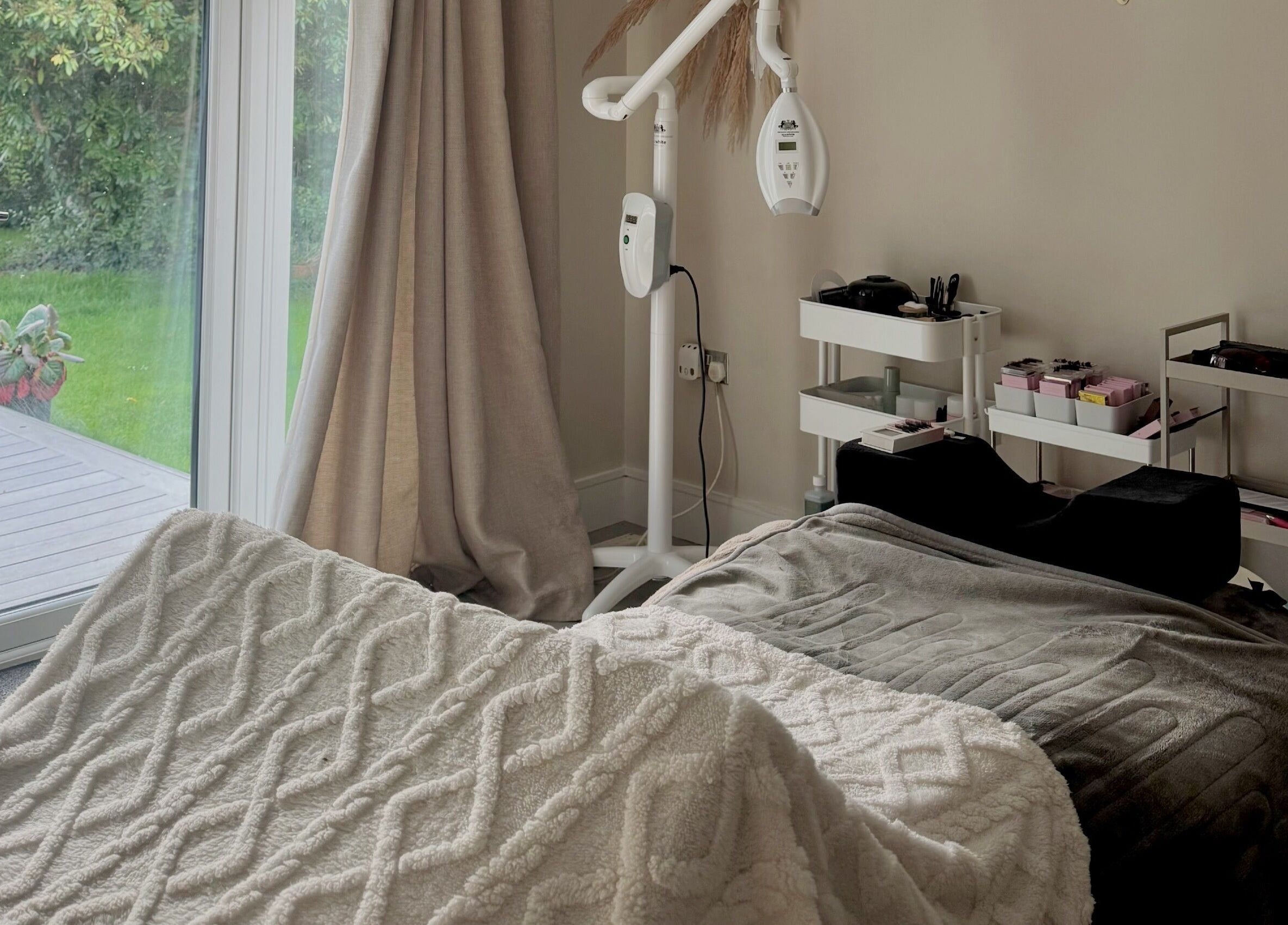 Cozy treatment room at Amber Rose Beauty, Poole, England, GB with a massage bed and garden view.