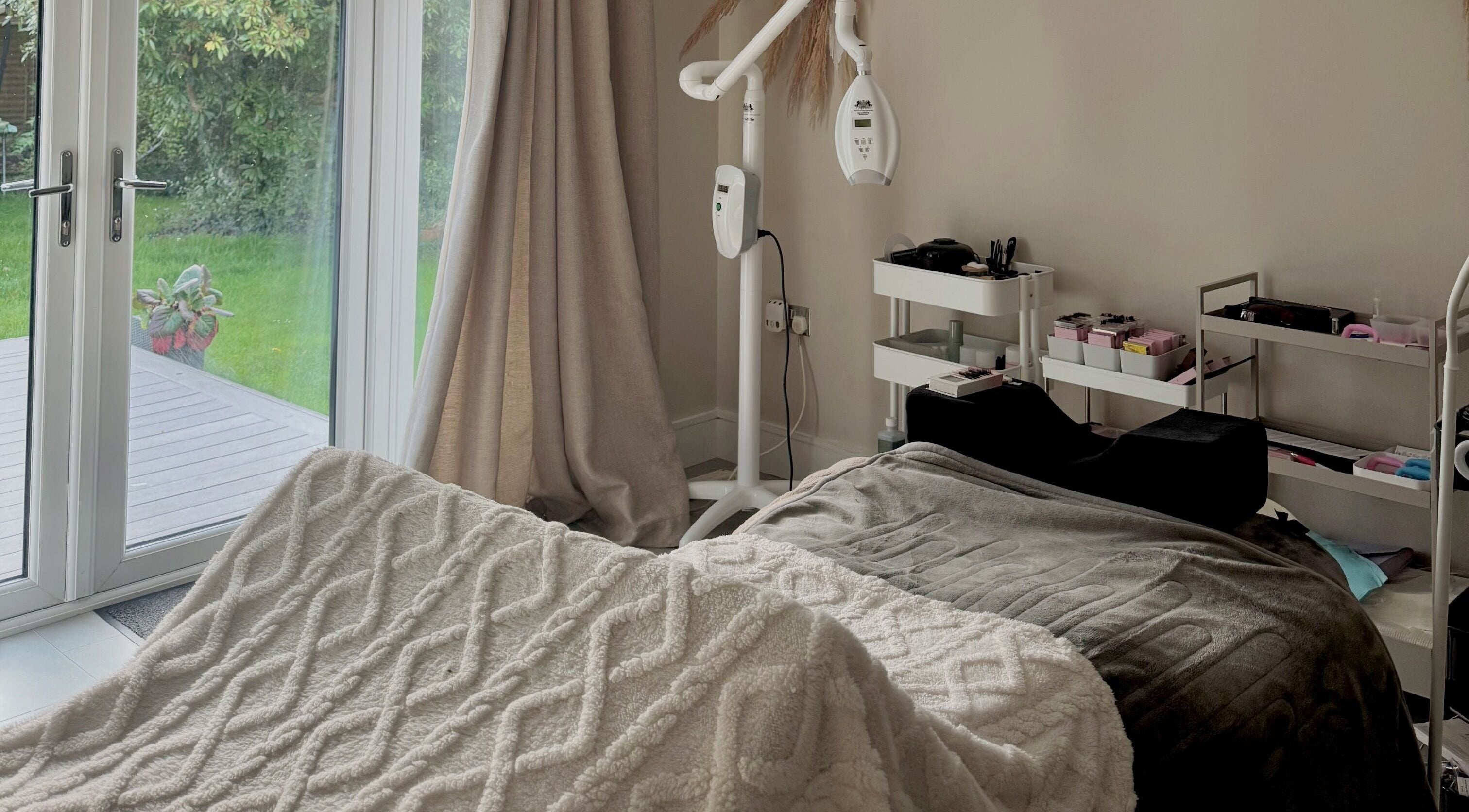 Cozy treatment room at Amber Rose Beauty, Poole, England, GB with a massage bed and garden view.