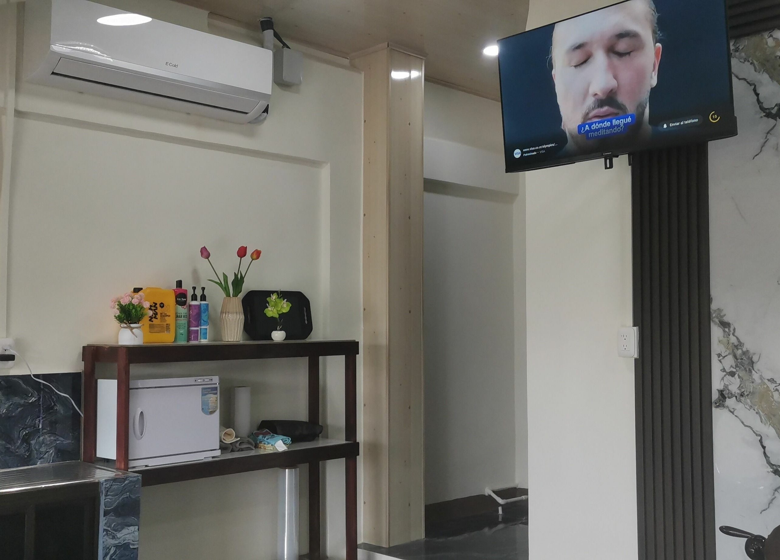 Interior de G Matices Barber en Guápiles, Limón, CR con estante decorativo y pantalla.