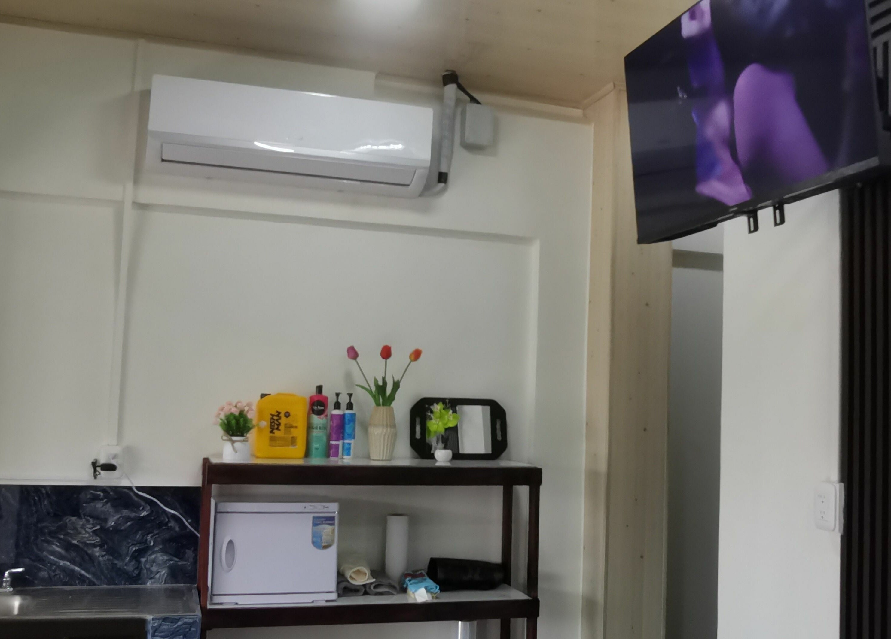 Interior del G Matices Barber en Guápiles, Limón, CR con estante, aire acondicionado y televisión.