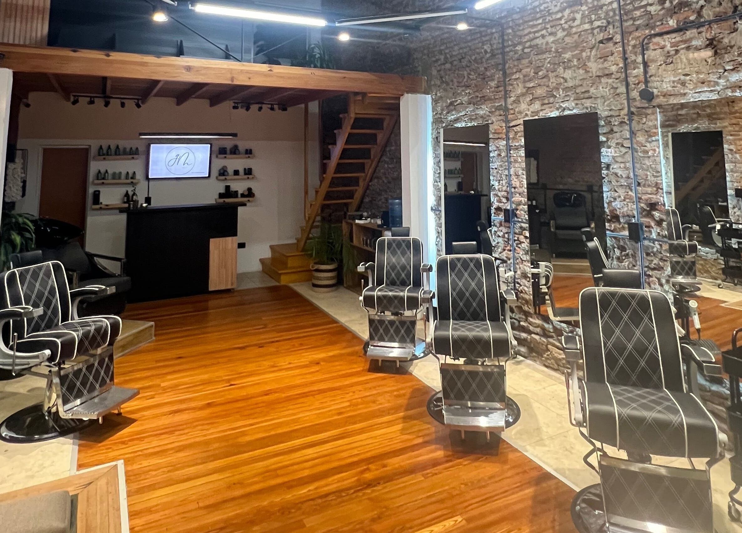 Interior de GM en Gualeguaychú, Entre Ríos, AR: sillas de peluquería modernas y paredes de ladrillo a la vista.