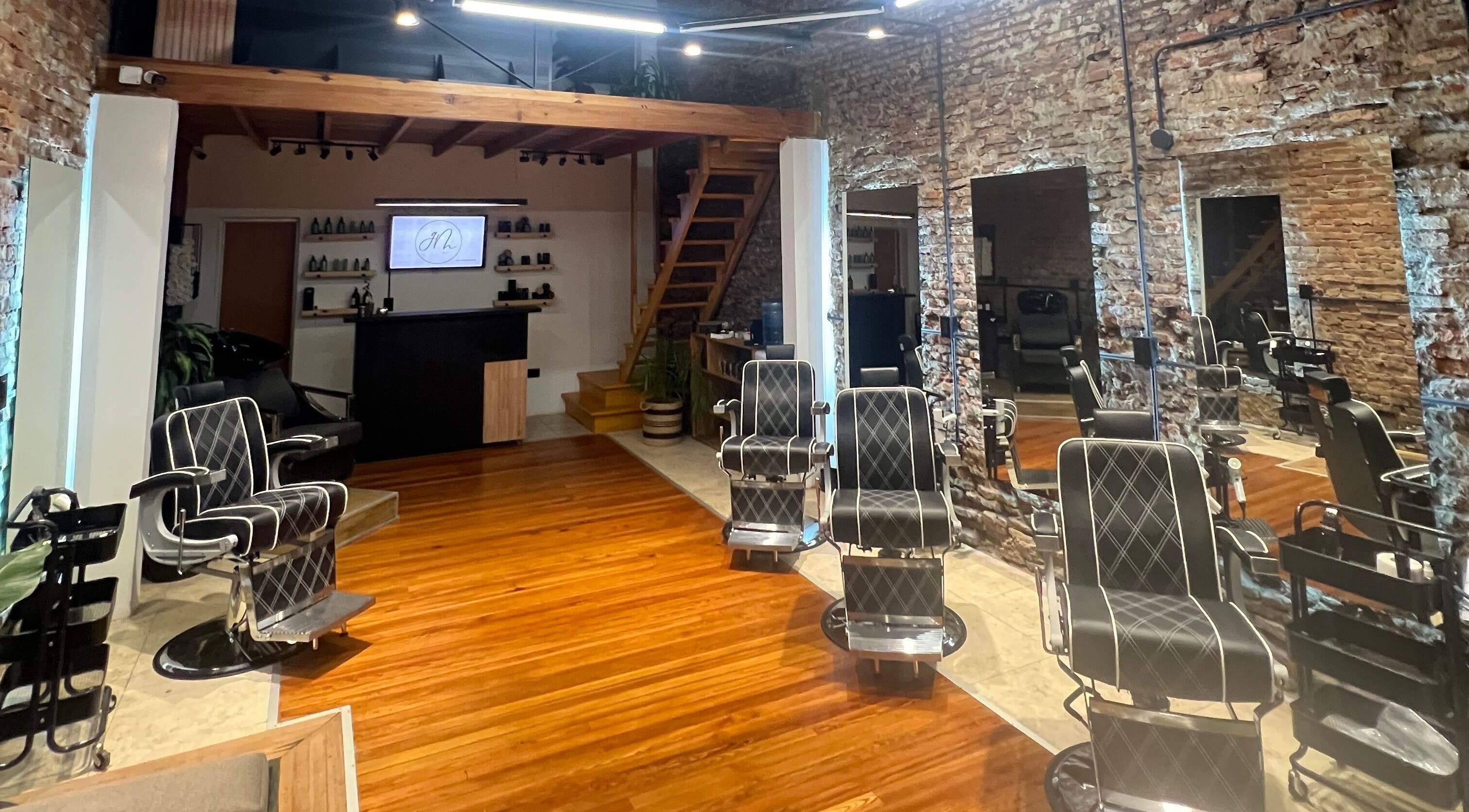 Interior de GM en Gualeguaychú, Entre Ríos, AR: sillas de peluquería modernas y paredes de ladrillo a la vista.