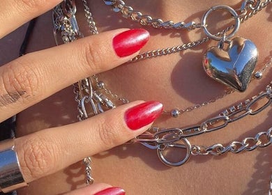 Mano con uñas rojas y collares brillantes en Pink Studio, San Isidro, Provincia De Buenos Aires, AR.
