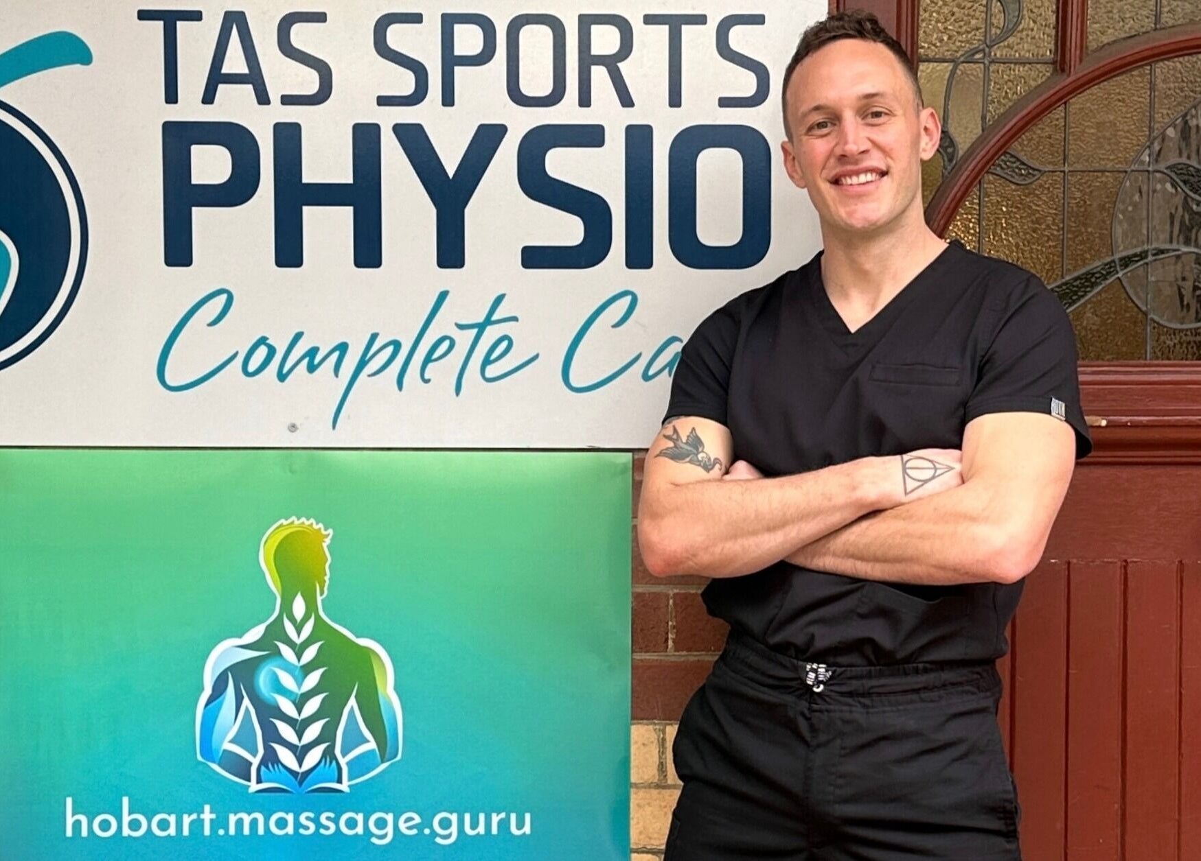 Professional at Hobart Massage Guru in Hobart, Tasmania, AU smiles beside clinic signage.