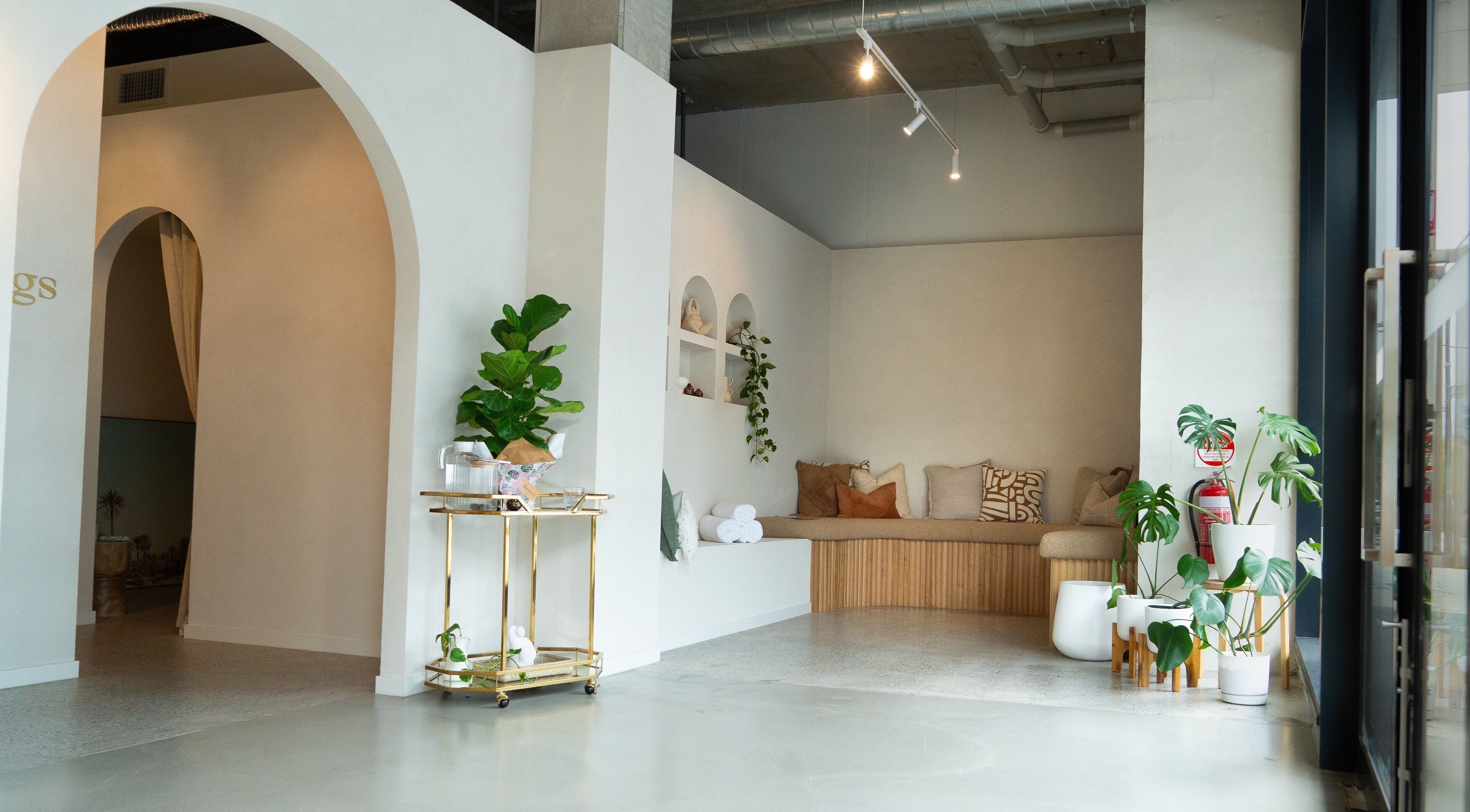 Serene lounge at Kalm Springs in Melbourne, Victoria, AU, featuring cozy seating and lush greenery.